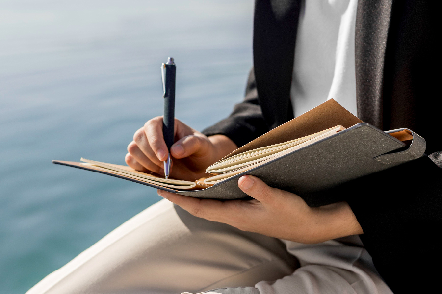 persona escribiendo en una libreta un ritual de gratitud frente al mar